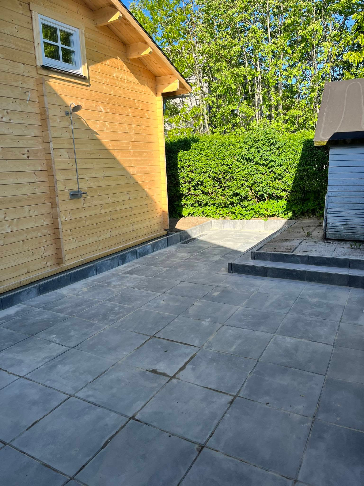 Færdig flisebelagt terrasse ved udhus i have